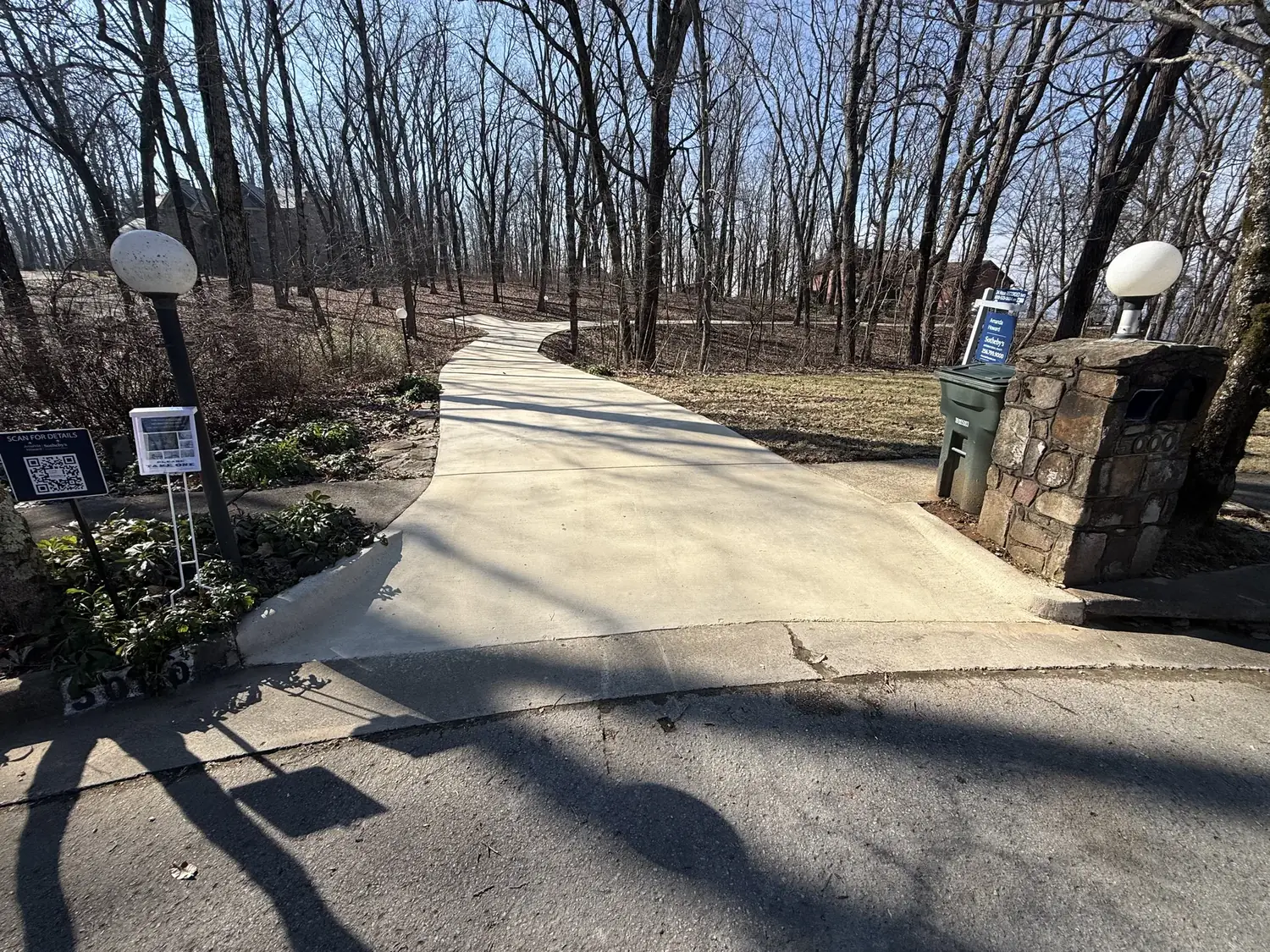 Clean concrete driveway through a wooded property