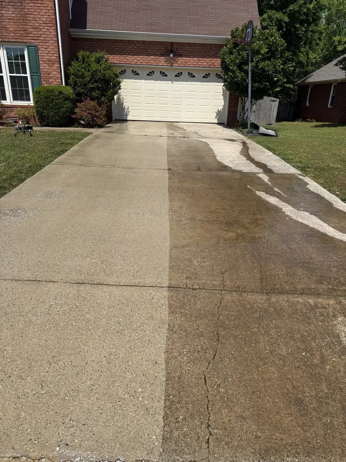 Concrete driveway pressure washing with a visible cleaning pass