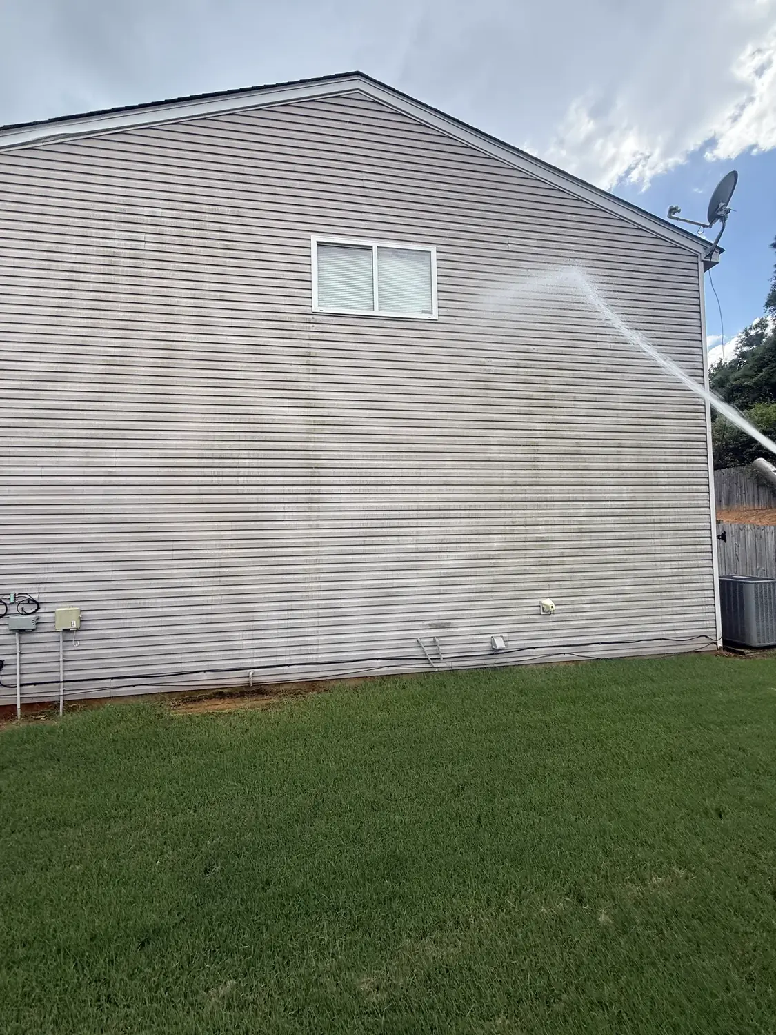 Soft wash solution being applied to two-story vinyl siding